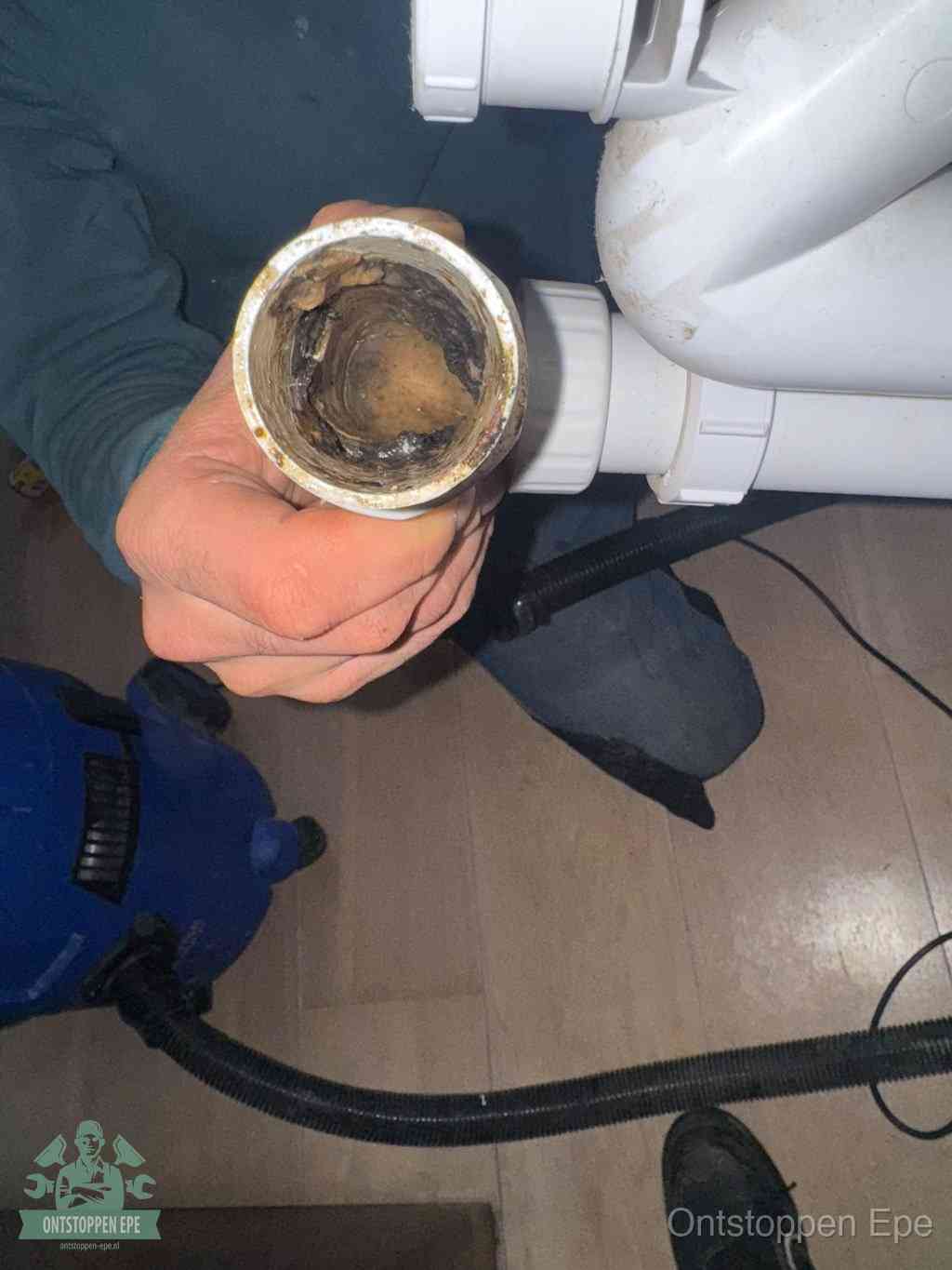 Een losgekoppeld PVC-afvoerbuisstuk dat van binnen volledig is dichtgeslibd met vet en vuil, de meest voorkomende oorzaak van verstoppingen in Epe