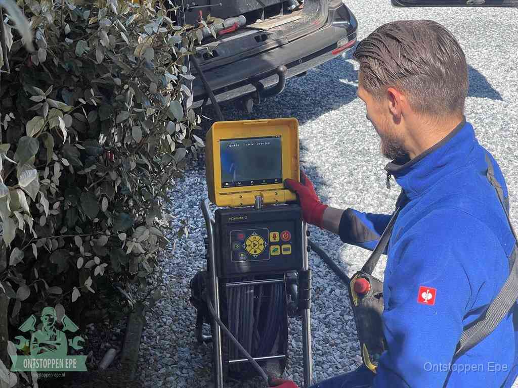 Een monteur bedient een rioolinspectiecamera met monitor en haspel om de verstopping in beeld te brengen in Epe