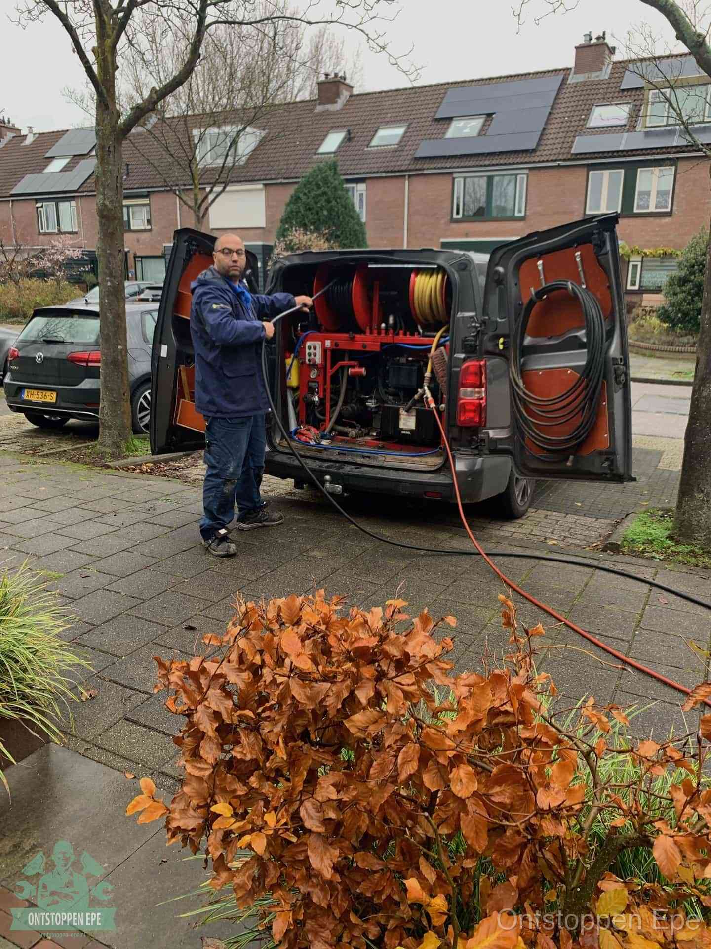 Een monteur staat bij zijn open bestelbus met hogedruk-rioolreinigingsapparatuur, klaar om binnen 30 minuten uit te rukken voor een spoedverstopping in Epe