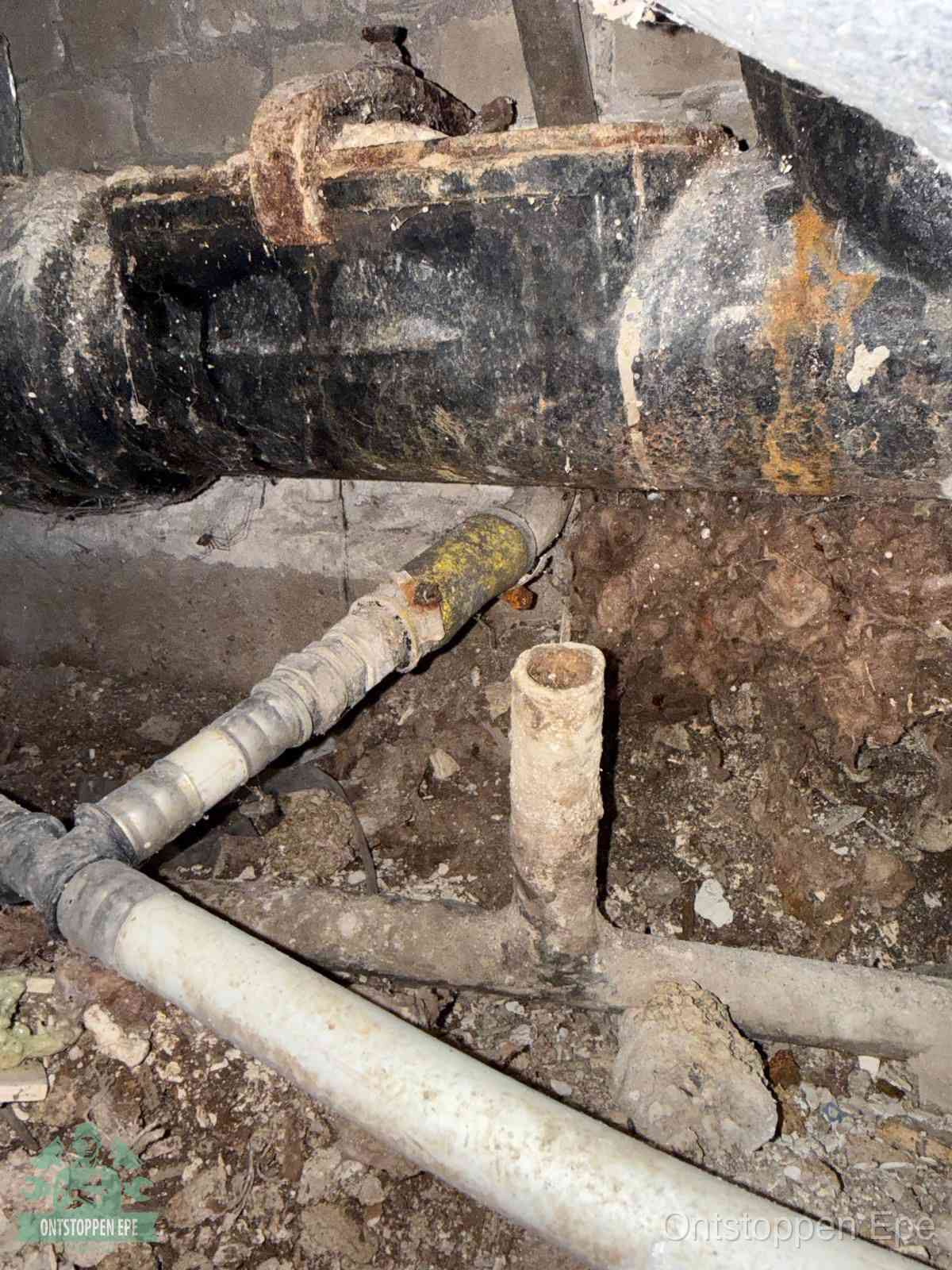 Een oude hoofdrioolbuis met roest- en kalkaanslag in een kruipruimte, oorzaak van terugkerende structurele rioolproblemen in Epe