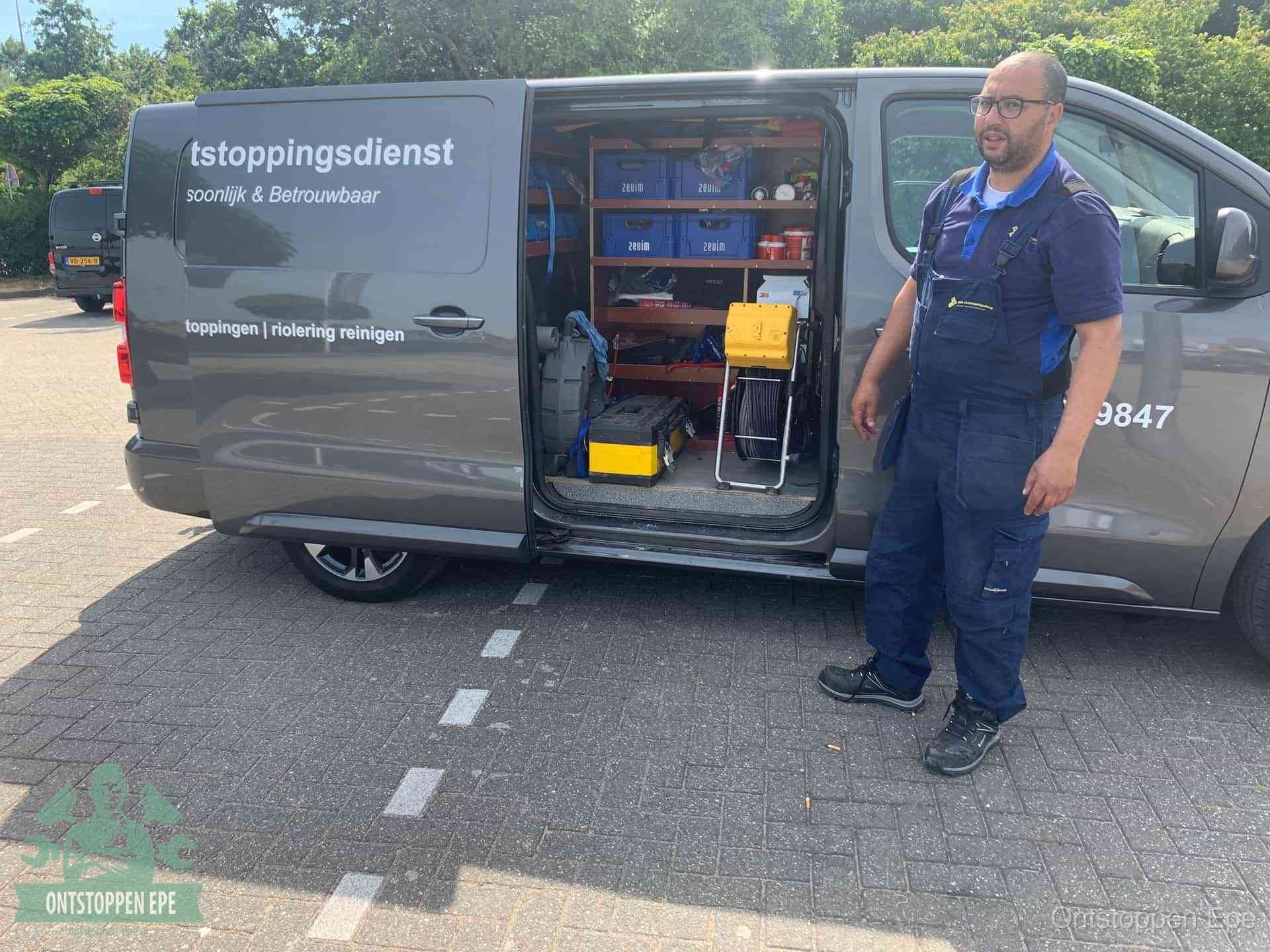Een monteur staat klaar bij zijn bedrijfsbus met gereedschap, de vaste werkwijze van de ontstoppingsdienst in Epe